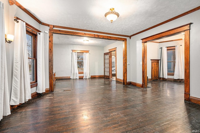 empty room with a textured ceiling, dark hardwood / wood-style flooring, and crown molding