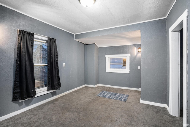 unfurnished room featuring dark colored carpet, a textured ceiling, and ornamental molding