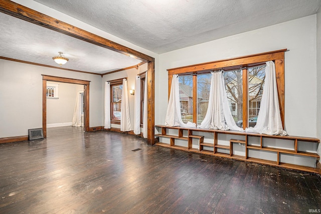 spare room featuring a textured ceiling, dark hardwood / wood-style flooring, and crown molding