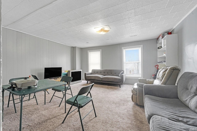 carpeted living room featuring wooden walls