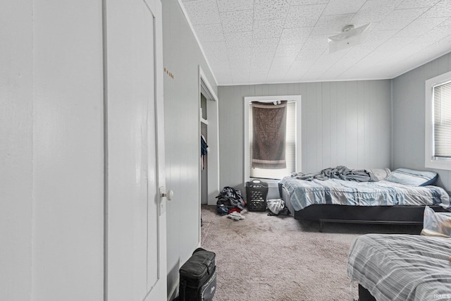 carpeted bedroom featuring wood walls