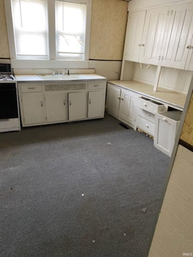 kitchen featuring sink, white cabinetry, and range