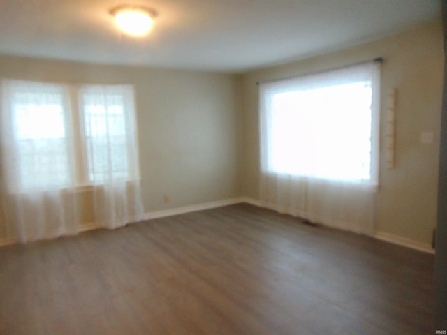 spare room with a healthy amount of sunlight and dark hardwood / wood-style floors