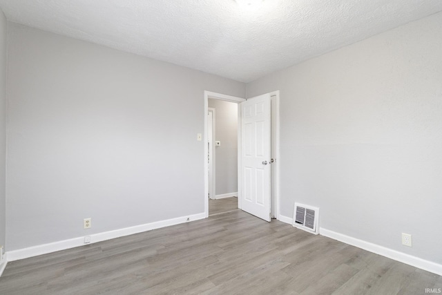 empty room with hardwood / wood-style floors and a textured ceiling