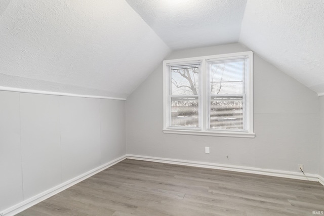 bonus room with hardwood / wood-style flooring, a textured ceiling, and vaulted ceiling