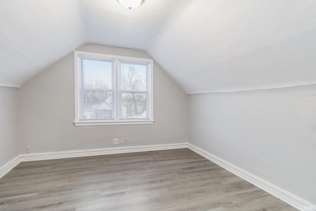 additional living space with light wood-type flooring and vaulted ceiling