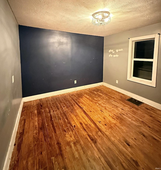 unfurnished room with wood-type flooring and a textured ceiling