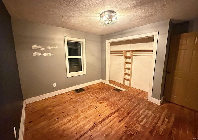 unfurnished bedroom featuring a closet, wood-type flooring, and a textured ceiling