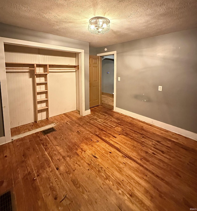 unfurnished bedroom featuring wood-type flooring, a textured ceiling, and a closet