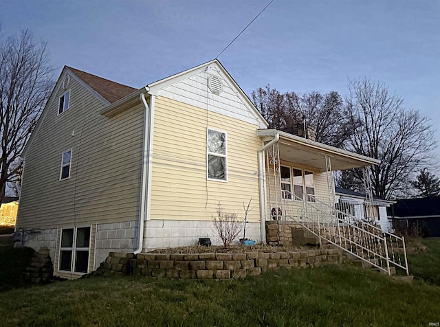 back of house with covered porch and a yard