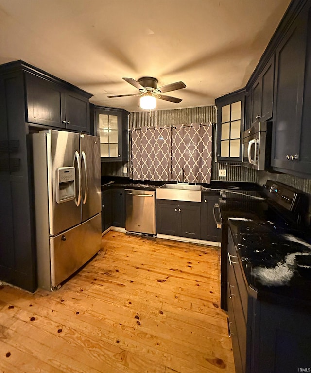 kitchen with decorative backsplash, stainless steel appliances, ceiling fan, sink, and light hardwood / wood-style flooring