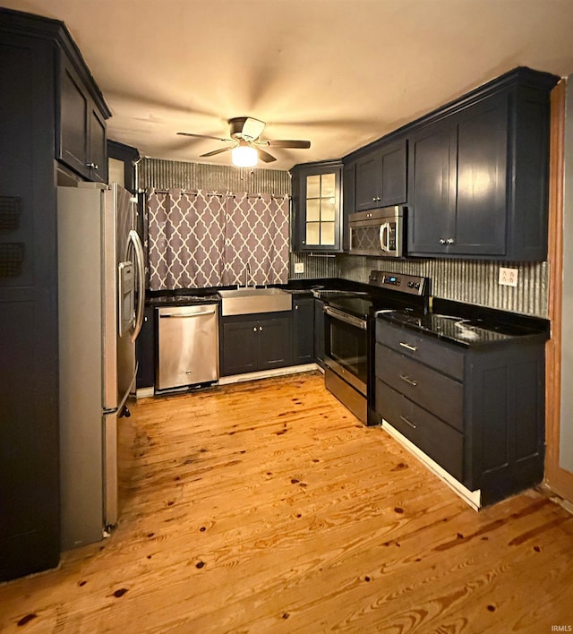 kitchen featuring ceiling fan, sink, light hardwood / wood-style flooring, decorative backsplash, and appliances with stainless steel finishes