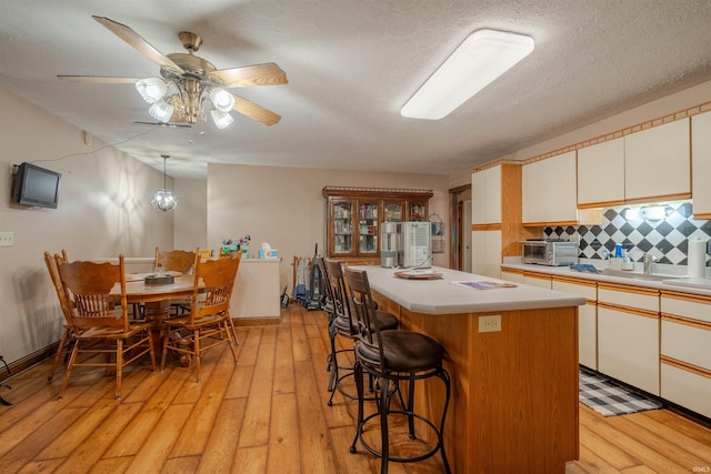 kitchen featuring backsplash, a center island, decorative light fixtures, and light hardwood / wood-style flooring