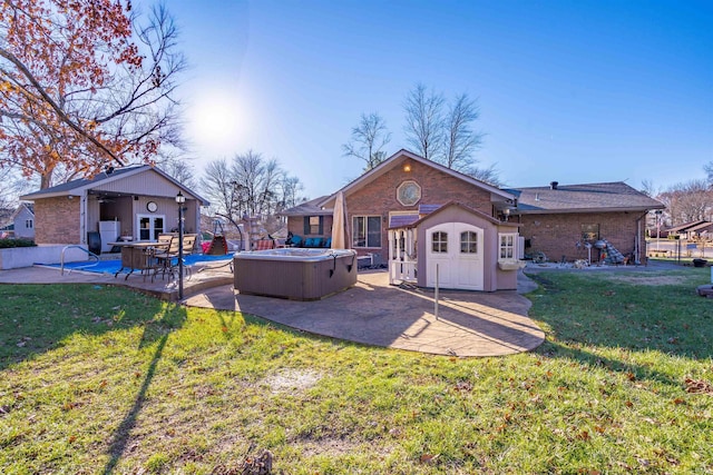 back of house with a yard, a hot tub, a storage unit, and a patio area