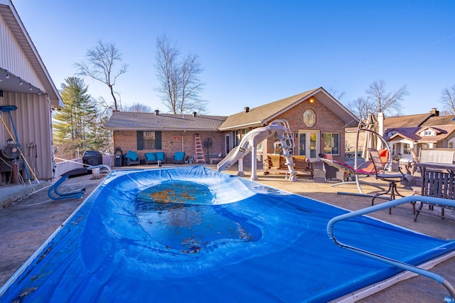 view of pool featuring a patio area, a water slide, and french doors