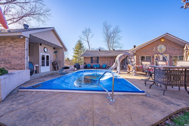 view of pool with french doors, a patio, and a water slide