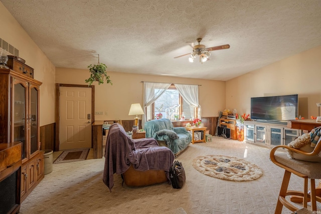 carpeted living room with ceiling fan and a textured ceiling