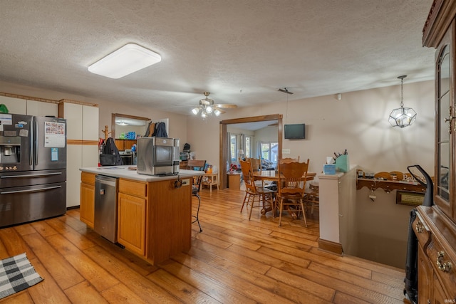 kitchen with ceiling fan, a center island, pendant lighting, appliances with stainless steel finishes, and light wood-type flooring