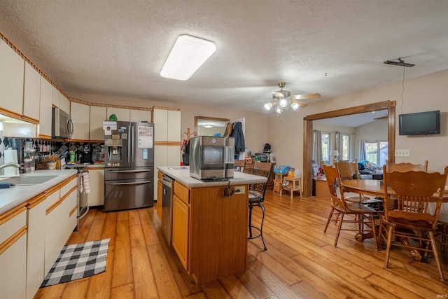 kitchen featuring white cabinets, a kitchen island, stainless steel appliances, and light hardwood / wood-style flooring