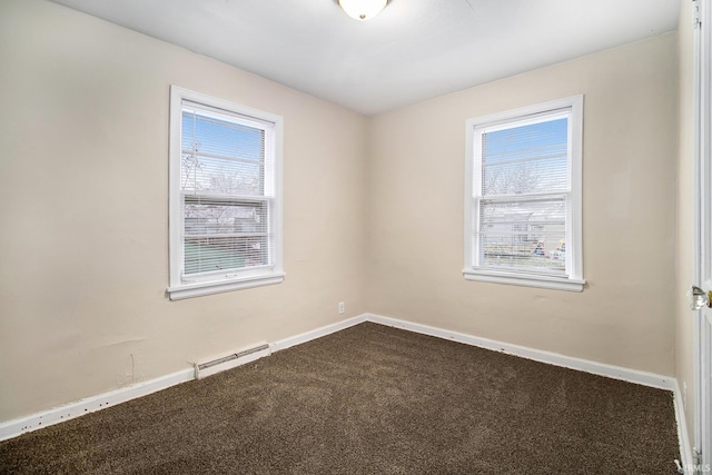 carpeted empty room featuring baseboard heating and a wealth of natural light