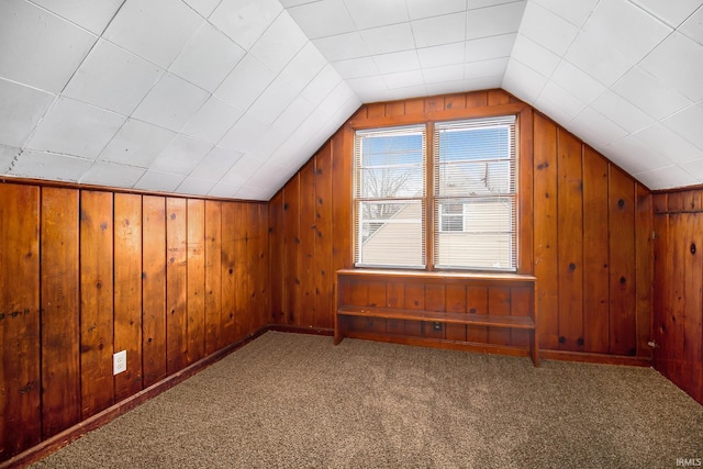 bonus room featuring carpet, vaulted ceiling, and wood walls