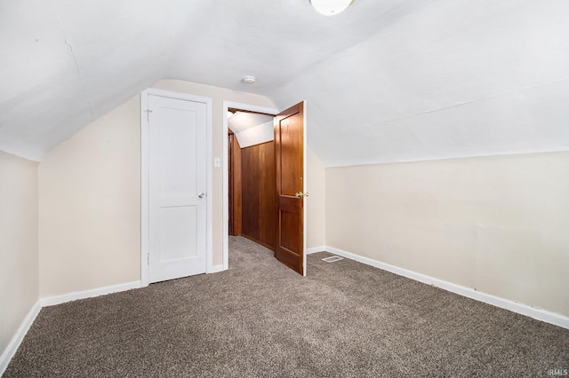 bonus room with dark colored carpet and lofted ceiling