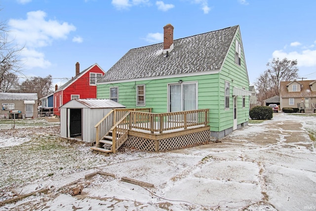 snow covered house featuring a shed and a deck