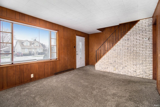 foyer featuring carpet flooring, baseboard heating, and wooden walls