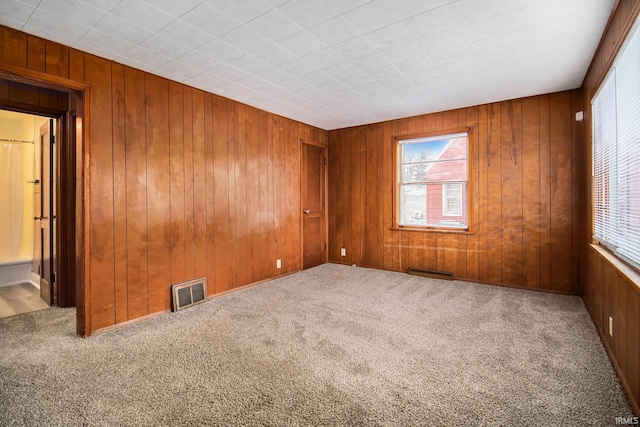 empty room with carpet floors and wooden walls