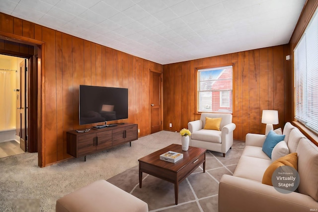 living room with light colored carpet, plenty of natural light, and wood walls