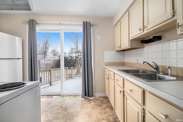 kitchen featuring backsplash, sink, white fridge, and cream cabinetry