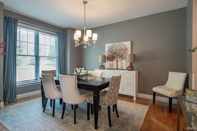 dining area featuring hardwood / wood-style flooring and a notable chandelier