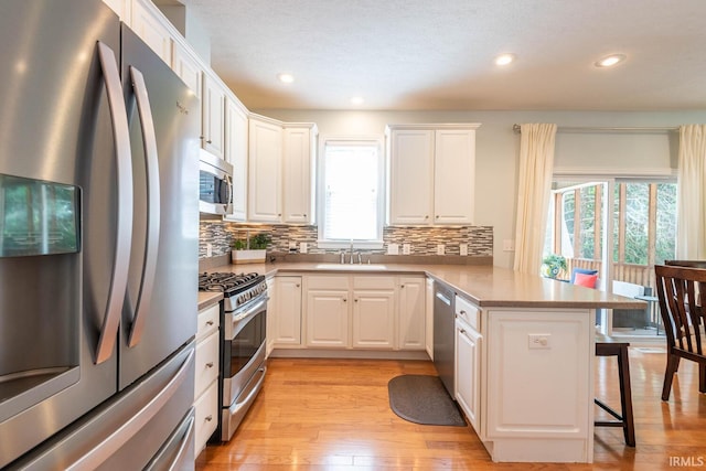 kitchen with kitchen peninsula, white cabinetry, plenty of natural light, and appliances with stainless steel finishes