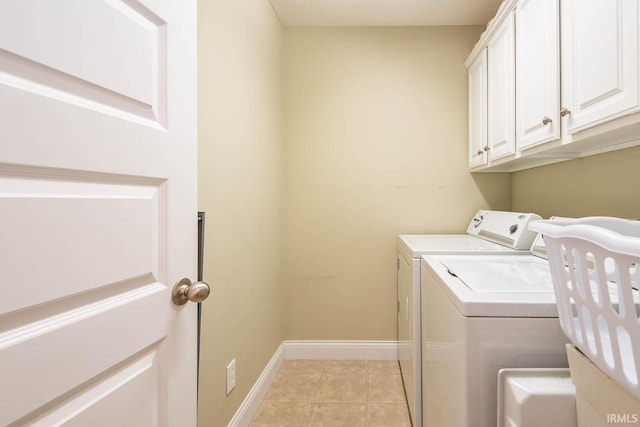 clothes washing area with washing machine and dryer, light tile patterned floors, and cabinets