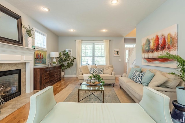 living room with a healthy amount of sunlight, light wood-type flooring, and a tiled fireplace