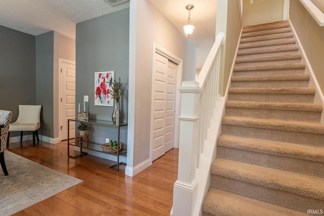 stairs featuring wood-type flooring and a textured ceiling