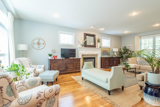 living room with light hardwood / wood-style floors, a wealth of natural light, and a tiled fireplace