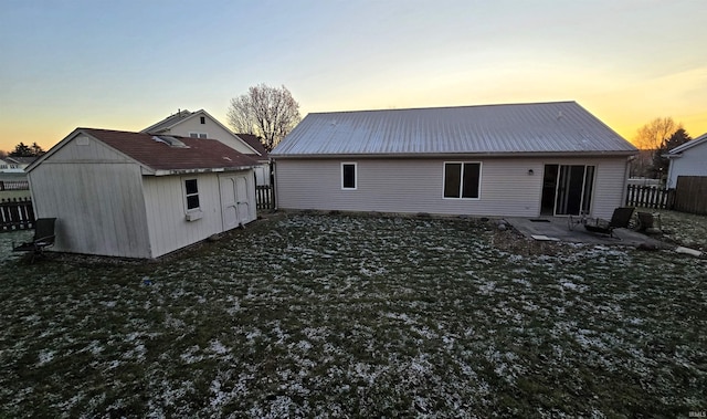 back house at dusk featuring a yard, a shed, and a patio area