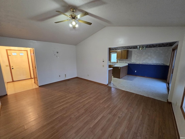 unfurnished living room featuring ceiling fan, dark hardwood / wood-style flooring, a textured ceiling, and vaulted ceiling