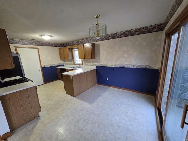 kitchen featuring decorative light fixtures, kitchen peninsula, a textured ceiling, and an inviting chandelier