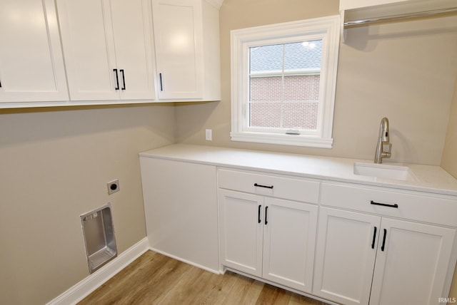 clothes washing area featuring cabinets, light hardwood / wood-style flooring, hookup for an electric dryer, and sink