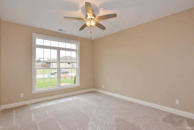 unfurnished room featuring ceiling fan, a healthy amount of sunlight, and light colored carpet