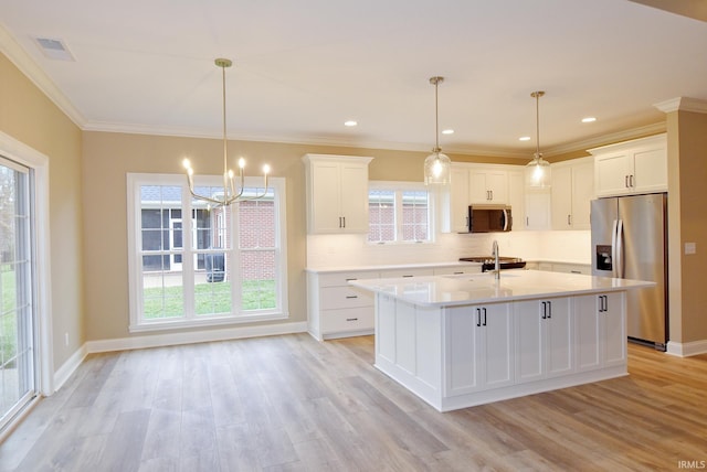 kitchen featuring appliances with stainless steel finishes, light wood-type flooring, white cabinetry, and hanging light fixtures