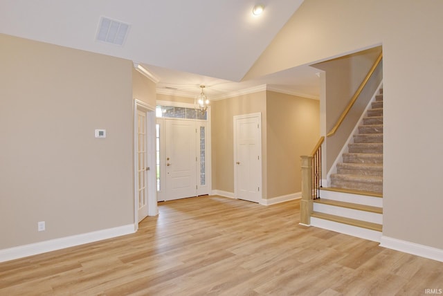 entrance foyer featuring lofted ceiling, light hardwood / wood-style flooring, a notable chandelier, and crown molding