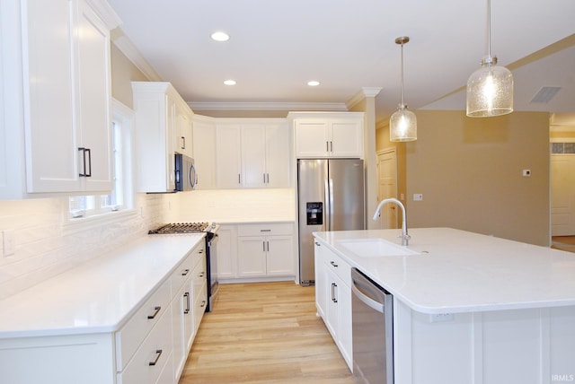 kitchen featuring white cabinets, appliances with stainless steel finishes, decorative light fixtures, and sink