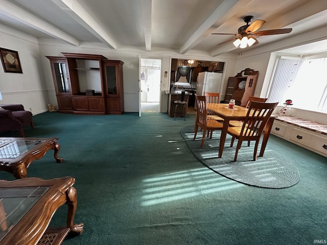 dining space with ceiling fan, beam ceiling, and dark carpet