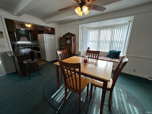 dining room featuring ceiling fan, beamed ceiling, and dark colored carpet