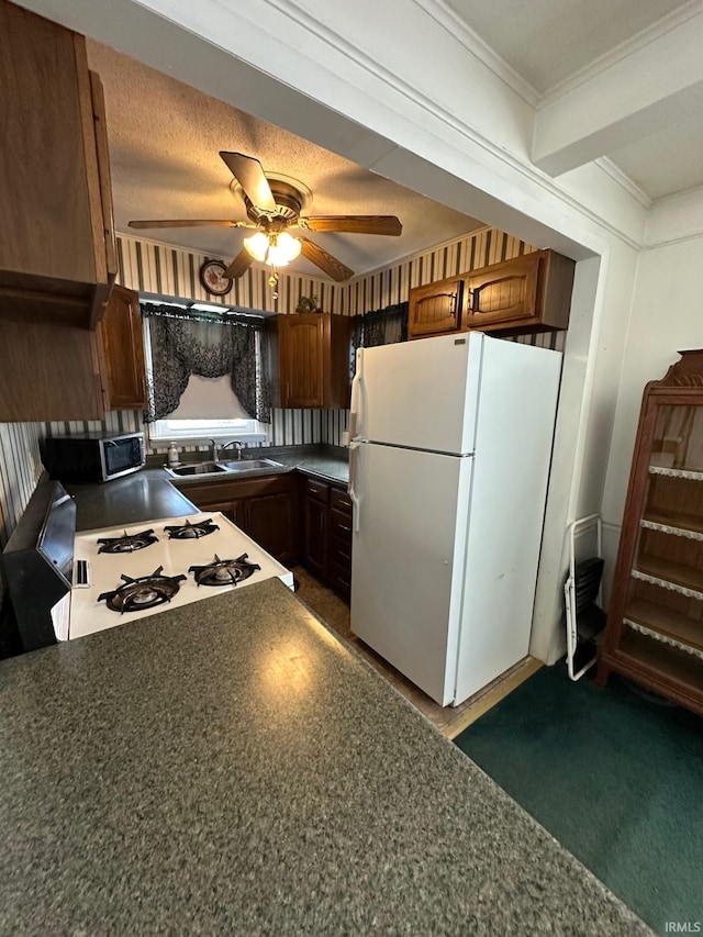 kitchen featuring a textured ceiling, ceiling fan, sink, range, and white fridge