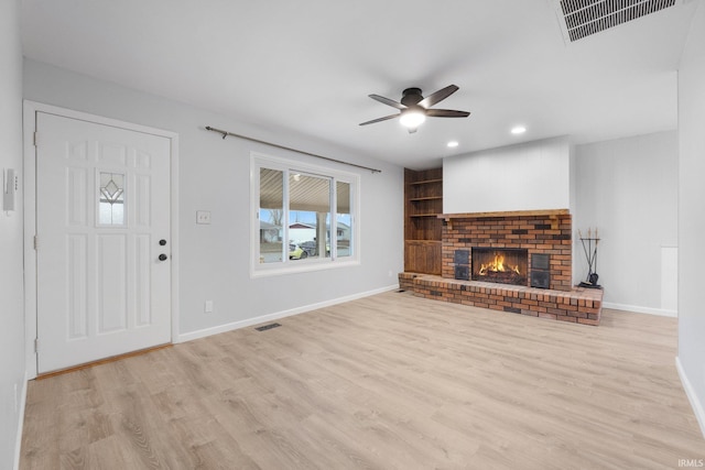 unfurnished living room featuring light hardwood / wood-style floors, a brick fireplace, and ceiling fan