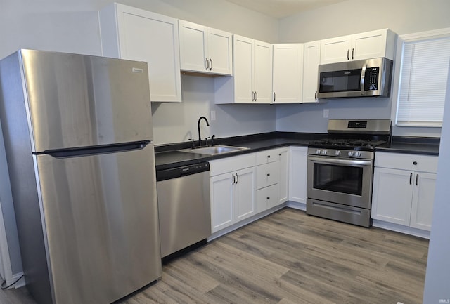 kitchen featuring hardwood / wood-style flooring, sink, white cabinetry, and stainless steel appliances